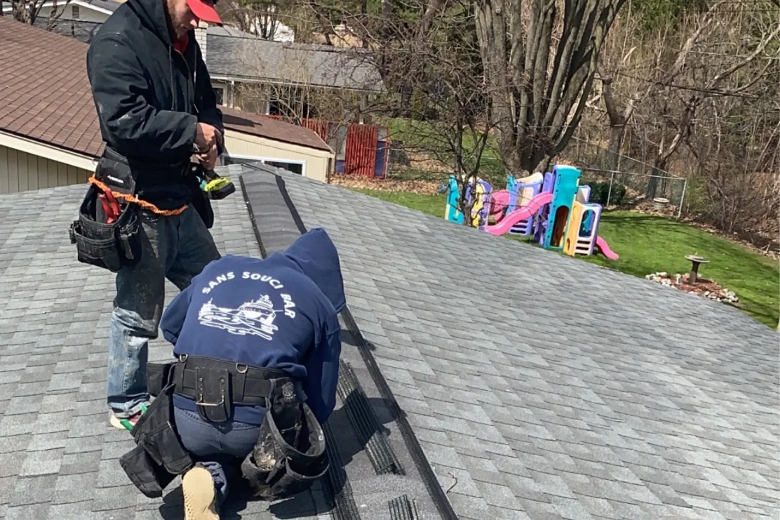 Technicians installing ridge vent bat exclusion on a Michigan roof