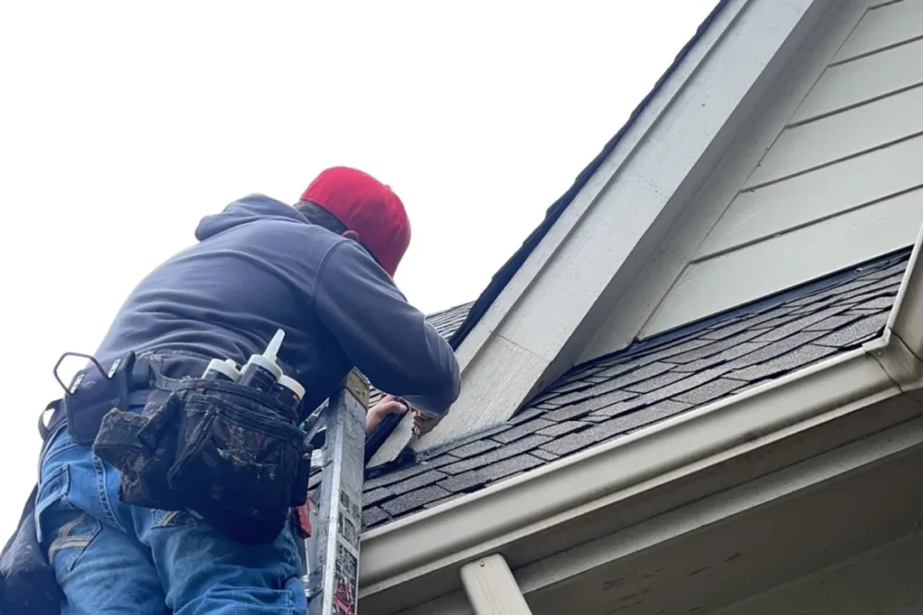 Technician on a ladder inspecting a soffit on a brick home